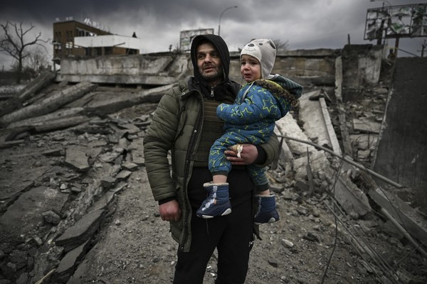 07 de março - Homem segura crianças durante fuga da cidade de Irpin, a oeste de Kiev, na Ucrânia. (Foto: Aris Messinis/AFP)
