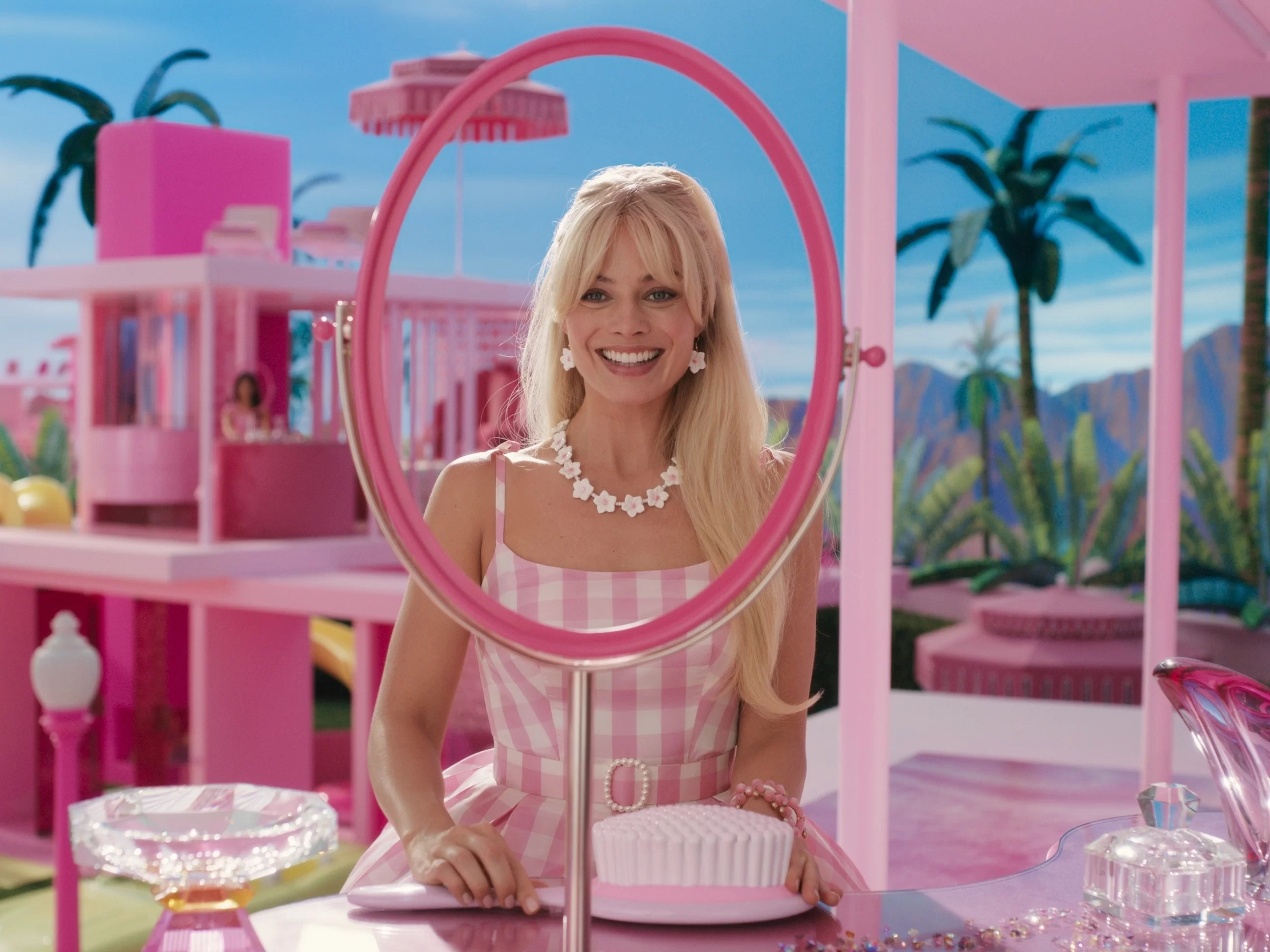 Barbie sorridente se observa no espelho de sua casa