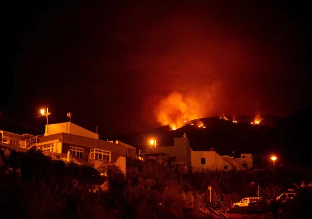 Foto noturna mostrando incêndio se aproximando das casas