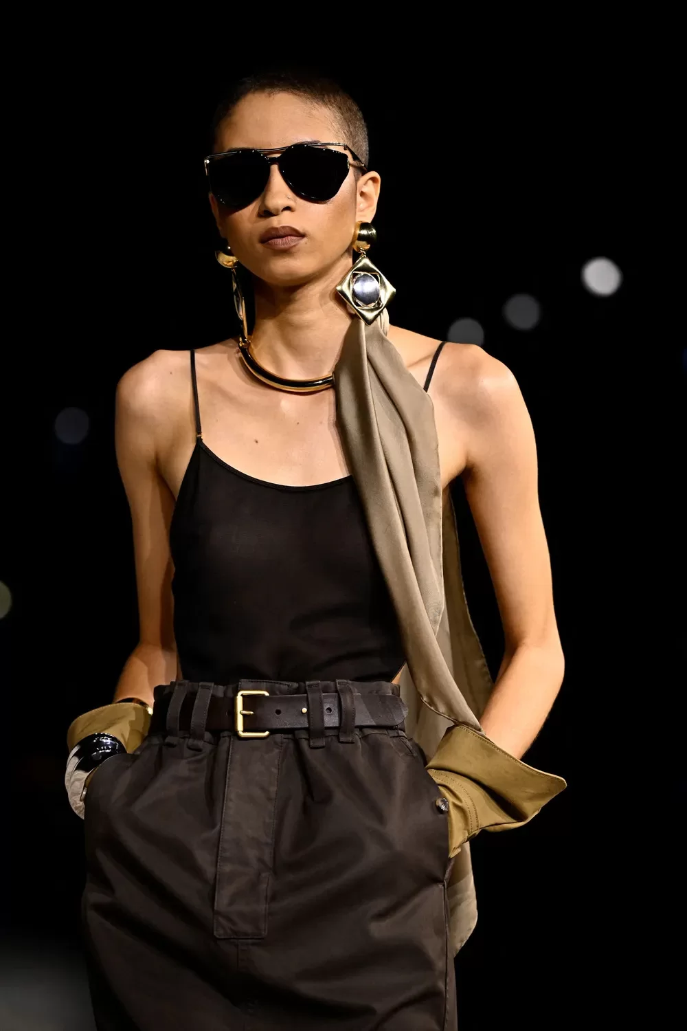 Modelo com brinco maxi em formato geométrico e luvas pesadas de couro no desfile da Saint Laurent na Paris Fashion Week 2024