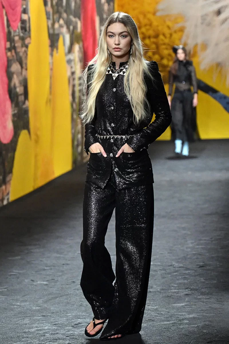 Gigi Hadid desfila na passarela da Chanel com brilhos da cabeça aos pés e simples chinelos pretos nos pés.