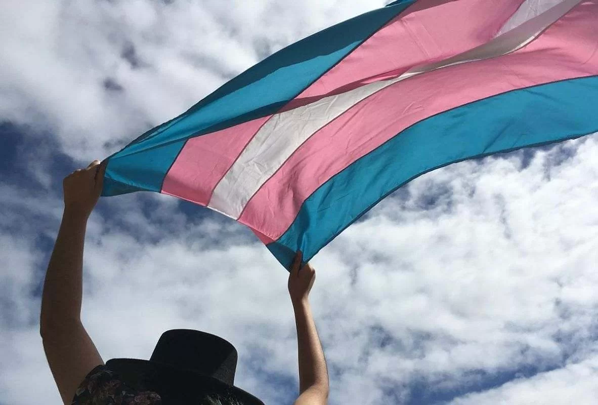Pessoa segurando a bandeira da comunidade trans