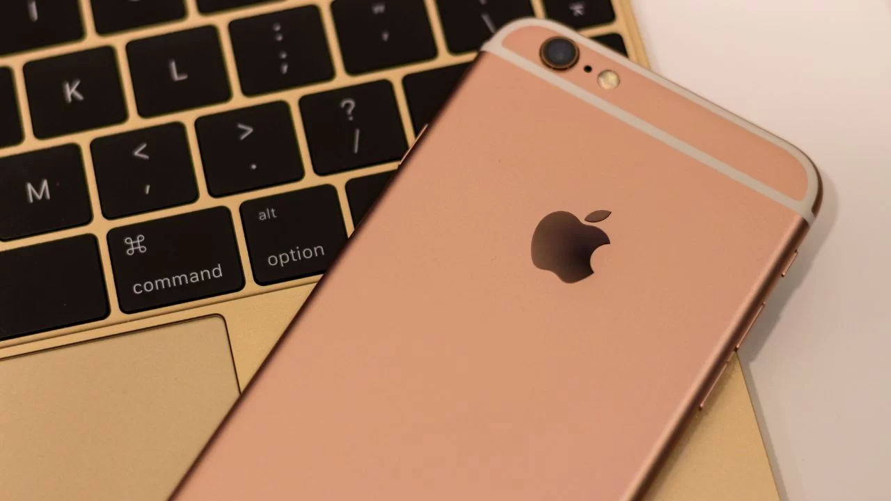 Celular da marca iphone,cor rosé sobre um notebook