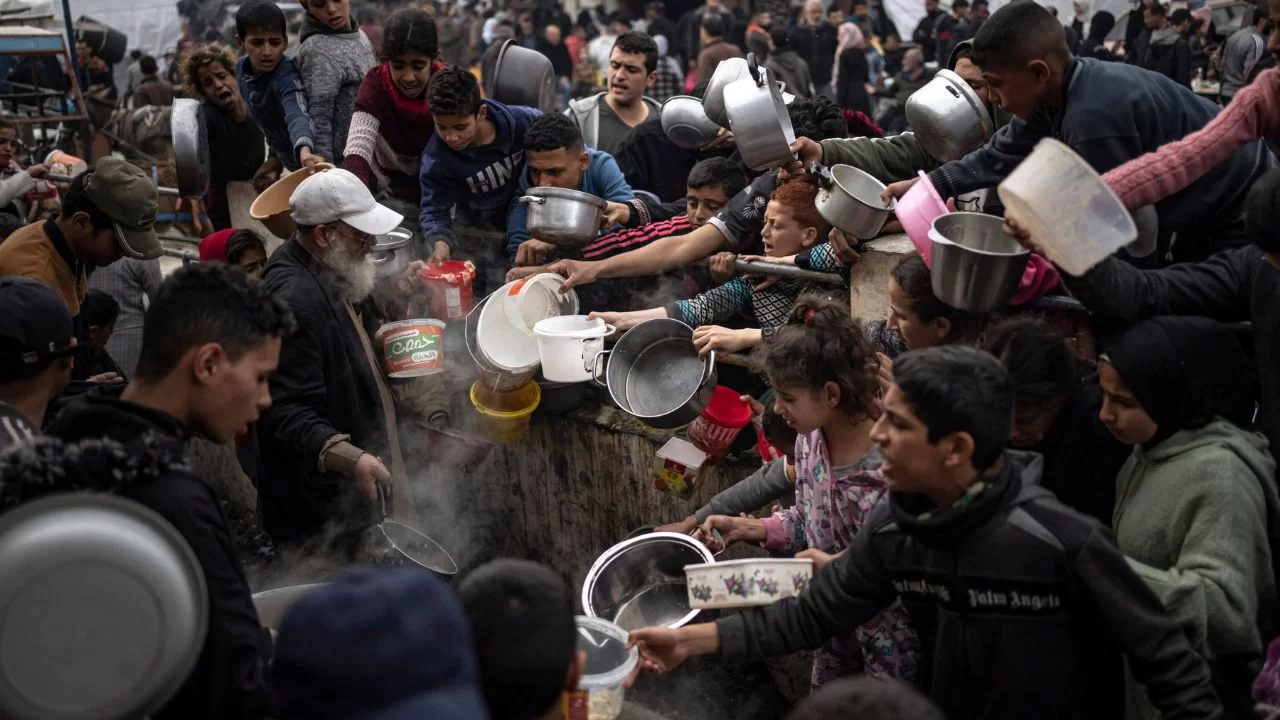 Os palestinos se aglomeram para receber uma refeição gratuita na cidade de Rafah, no sul de Gaza. 
