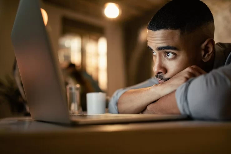 Jovem com tristeza aparente diante da tela de computador (Foto:Reprodução/Freepik)