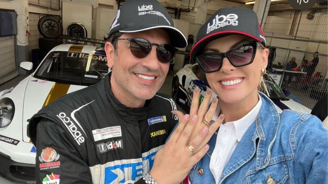 Edu Guedes e Ana Hickmann posam mostrando alianças de noivado
